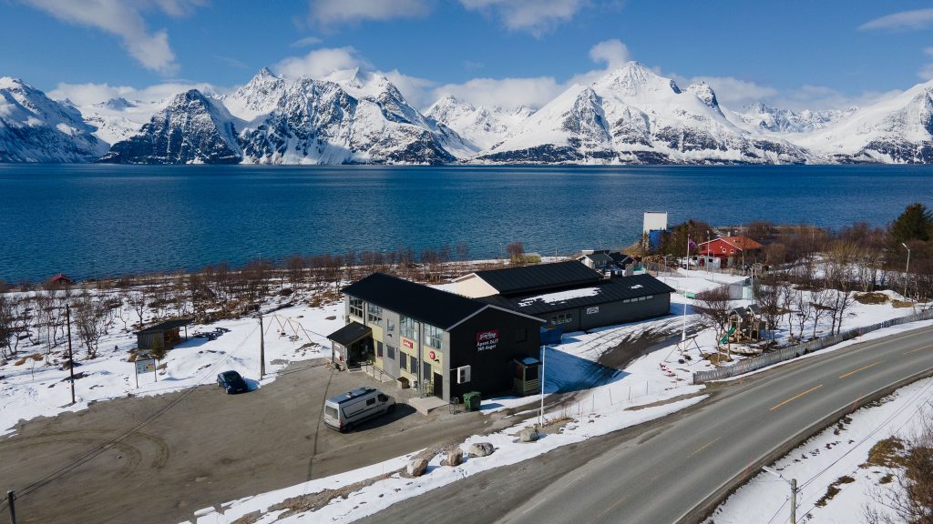 Butikken ligger sentralt plassert langs E6. I bakgrunnen ser man fjorden og høye fjell.