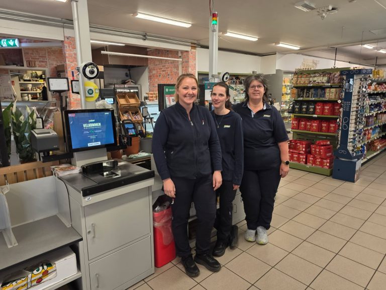 Teamet i Joker Knarrlagsund står ved de selvbetjente kassene i butikken.